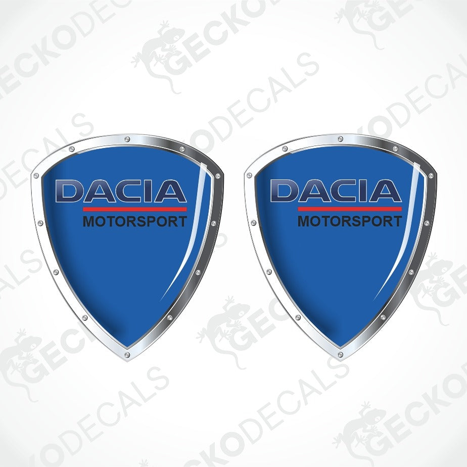 Two identical Dacia Motorsport shield-shaped decals on a white background with diagonal watermarks. The decals feature a light mint green center, silver metallic borders, and the Dacia Motorsport logo in blue and red.