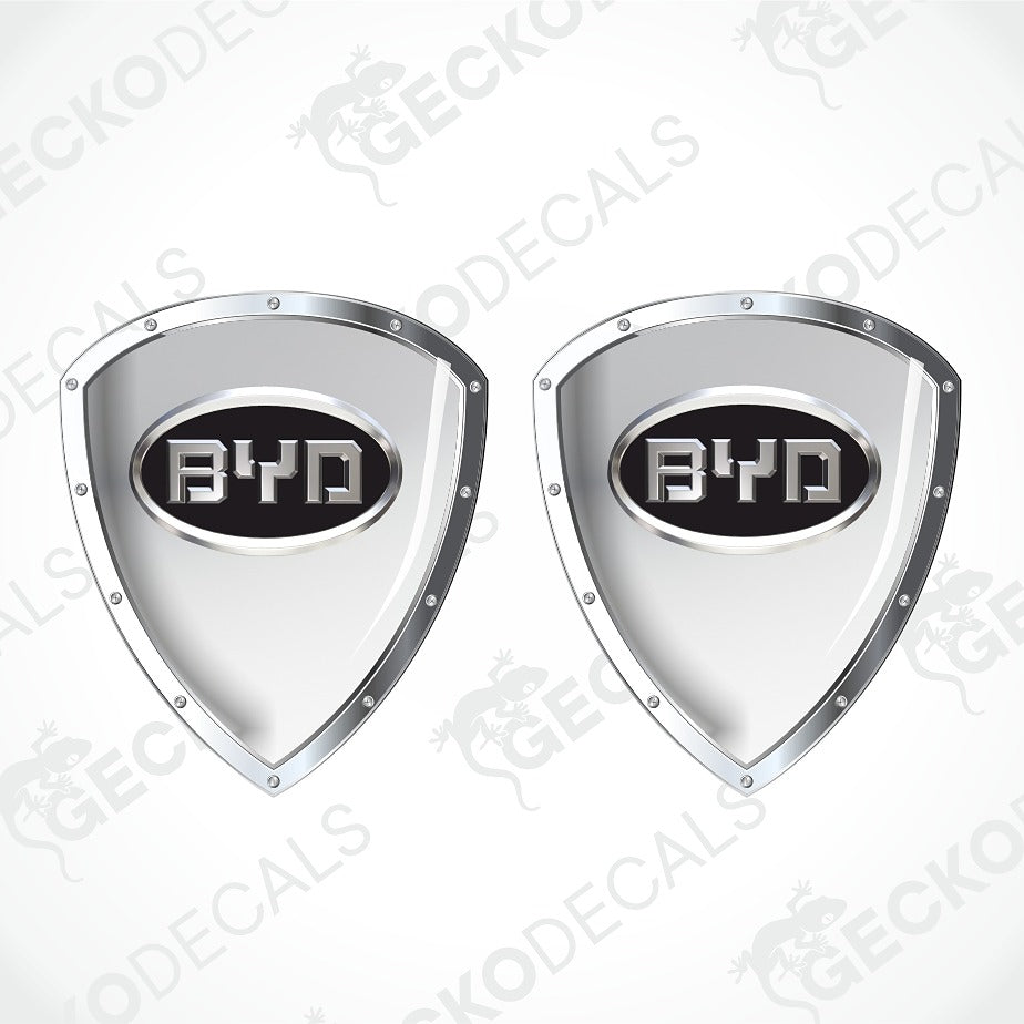 Two identical shield-shaped chrome car decals with a black center and the BYD logo, shown on a light gray background with a faint diagonal watermark.