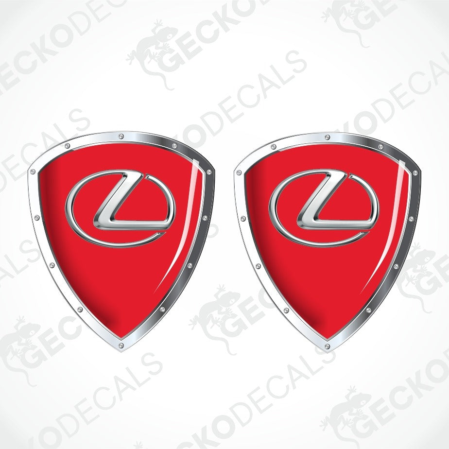 Two red shield-shaped Lexus decal stickers with silver metallic borders and the silver Lexus logo in the center, shown on a white background with a faint watermark pattern.