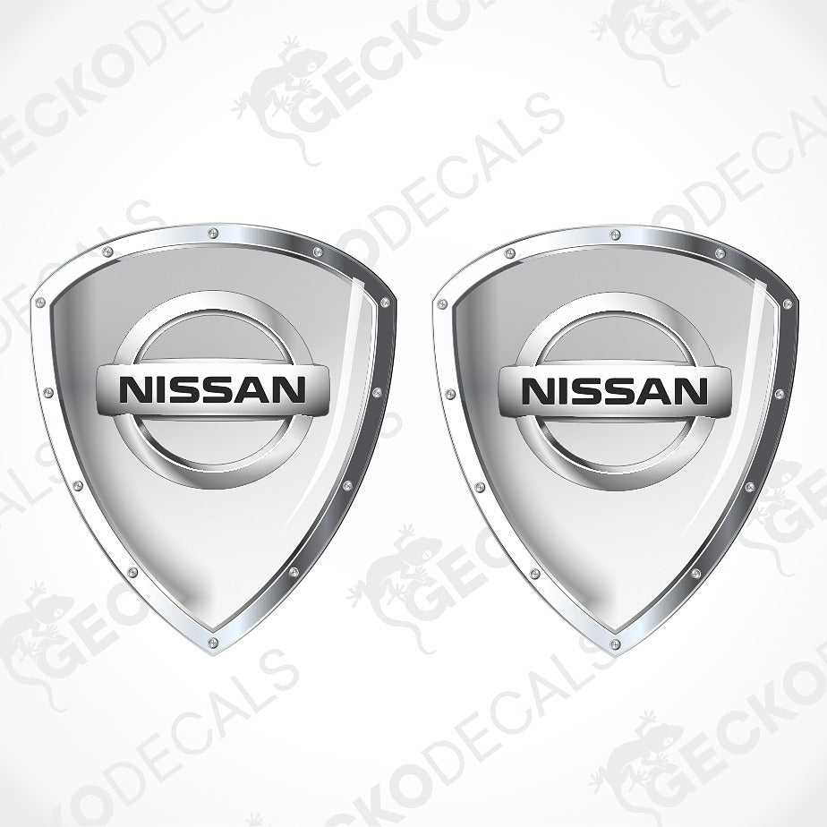 Two silver Nissan shield-shaped decal designs on a light gray background with diagonal watermark text.