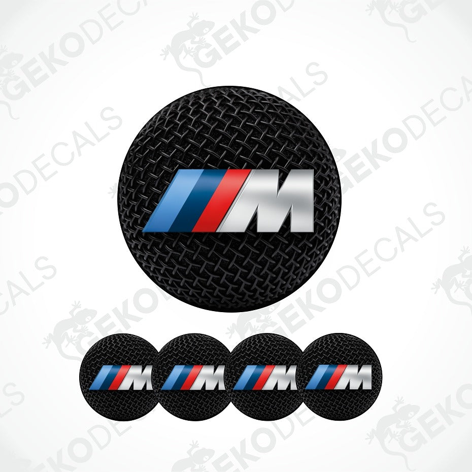 A set of circular black textured decal stickers featuring the BMW M logo with blue, red, and silver stripes. The main sticker is shown larger at the top, with four smaller matching stickers aligned horizontally below on a white background with faint watermark text.