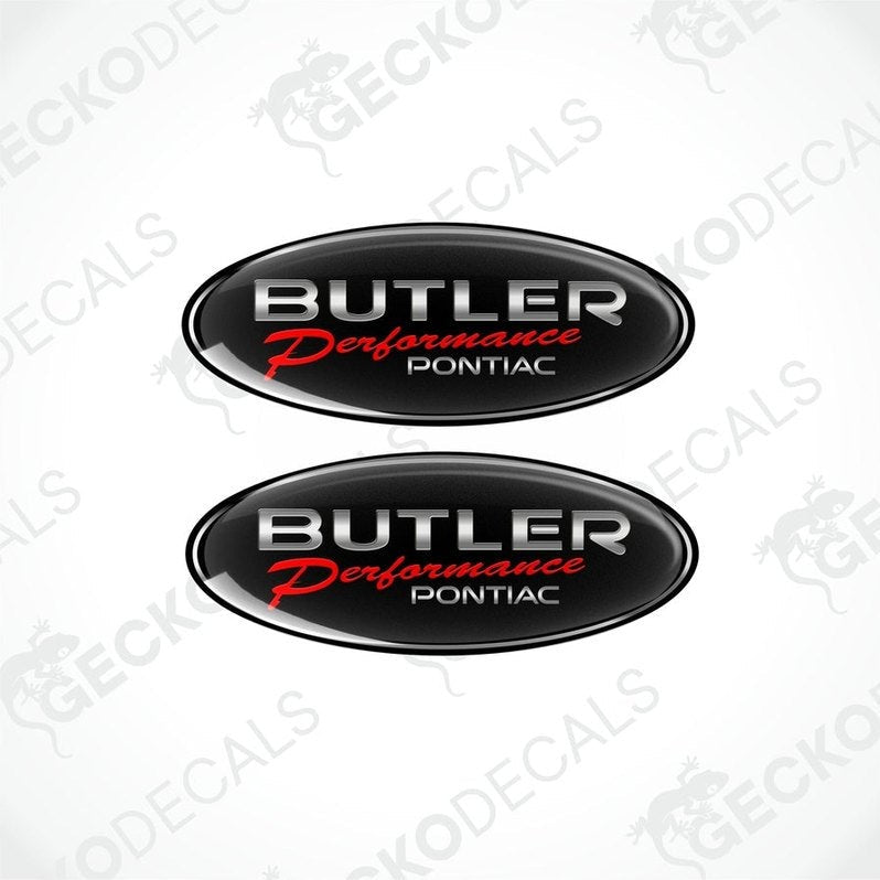 Two black oval vinyl stickers with a silver emblem design PONTIAC BUTLER PERFORMANCE , placed against a black background.