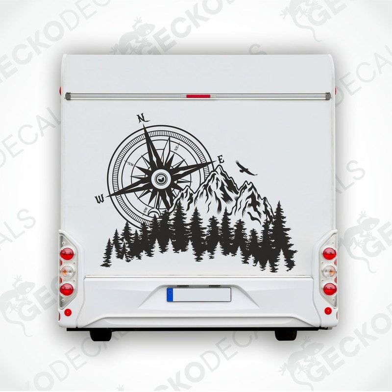A white car decal with a compass design, mountains, and pine trees.