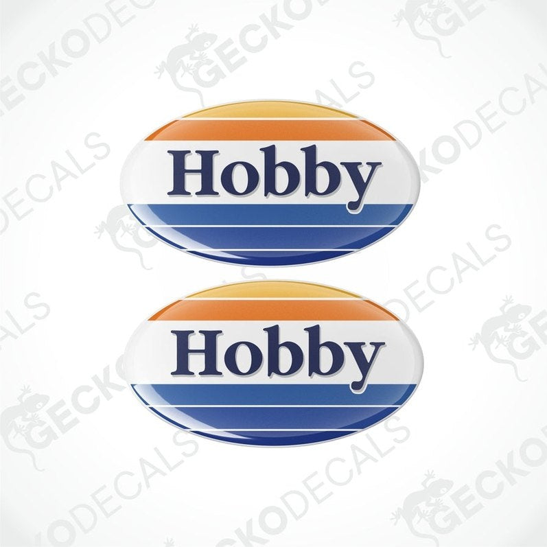 Two round vinyl decals with the word 'HOBBY' in bold letters, one above the other. The decals have a blue background with an orange and white border.