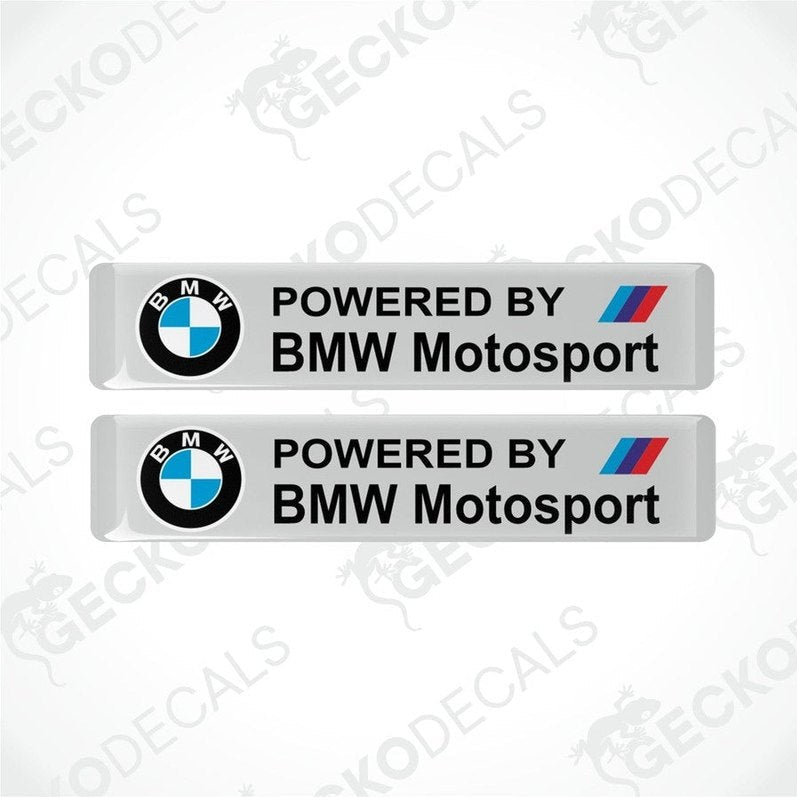 Two stickers with the BMW logo on a white background and the black text POWERED BY BMW MOTORSPORT