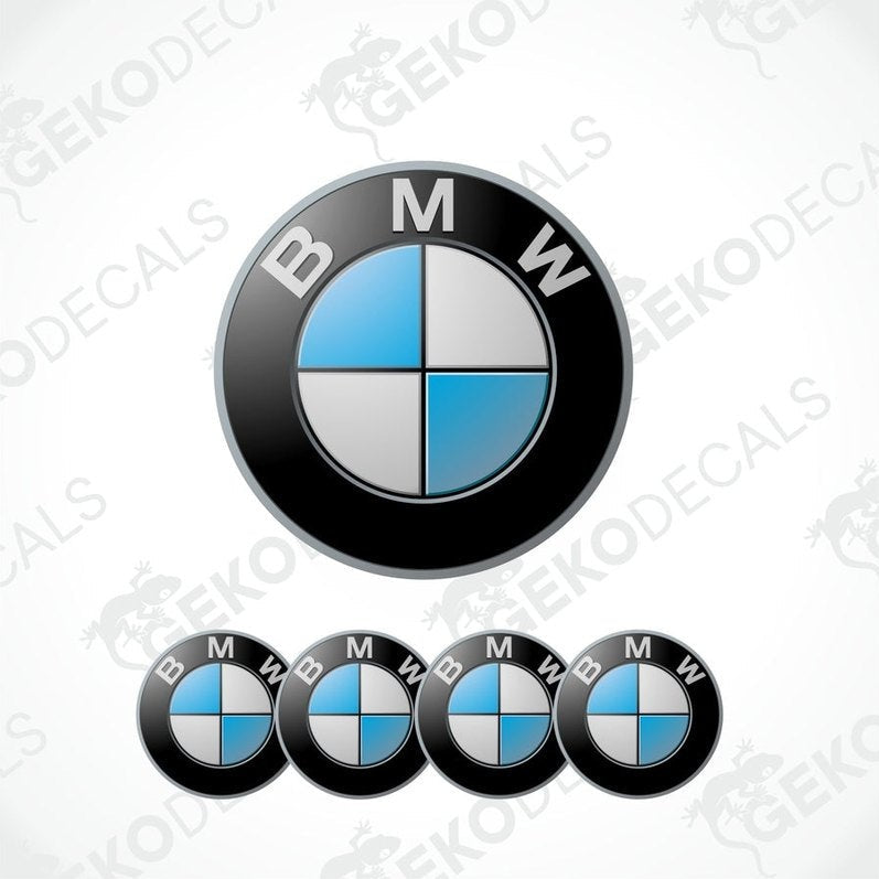 A set of four BMW emblem stickers, with one large emblem in the center and three smaller ones around it, all in black, blue, and white colors.