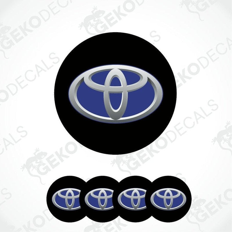 A set of four vinyl stickers with a Toyota brand logo, including two in black with a blue and silver Toyota emblem, and two in gray with a blue and silver Toyota emblem.