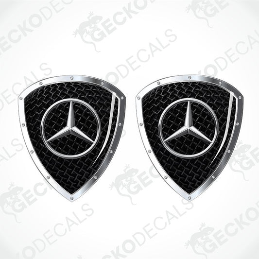 Two Mercedes-Benz shield-shaped decal stickers with a black diamond plate pattern and a silver three-pointed star logo, shown on a white background with diagonal watermarks.