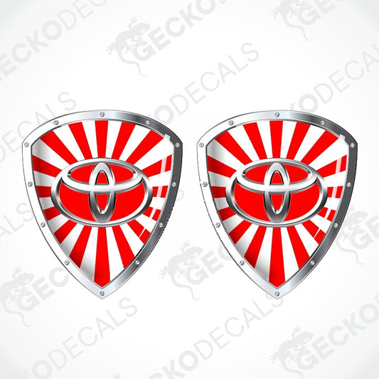 Two identical shield-shaped decals featuring the red and white Toyota logo over a red and white sunburst background, with silver metallic borders, shown on a light gray background with a faint GECKODECALS watermark.