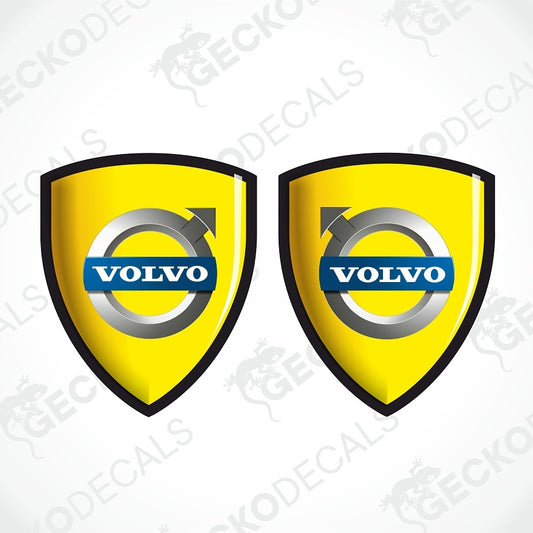 Two yellow Volvo shield-shaped decals with black borders, silver wheel-like rings, and blue Volvo logos on a white background with faint watermark text.