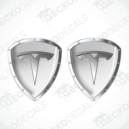 Two identical silver Tesla shield-shaped decals with the Tesla logo in the center, shown on a light gray background with diagonal watermark text.