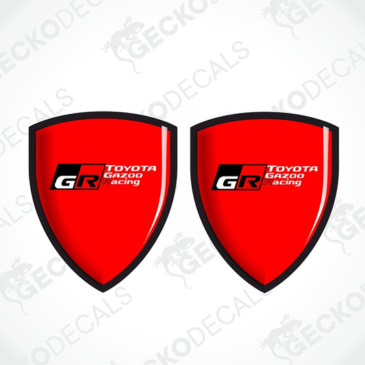 Two red shield-shaped decal stickers with black borders and the Toyota Gazoo Racing GR logo, displayed on a light gray background with diagonal watermarks.