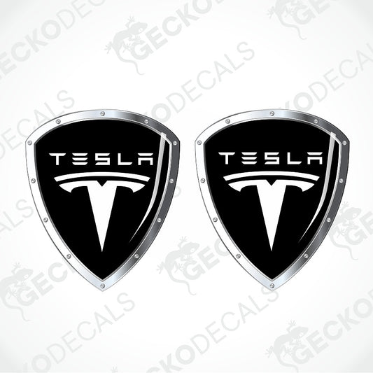Two black and silver Tesla shield-shaped decal emblems on a light gray background with diagonal watermarks.