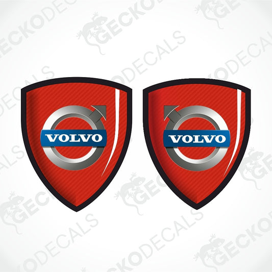 Two red Volvo shield-shaped decals with black borders, a carbon-fiber texture, and the blue and silver Volvo logo in the center, shown on a white background with a faint watermark.