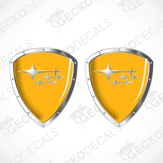 Two identical yellow car decal shields with silver borders and the Subaru logo, shown on a light gray background with diagonal watermarks.