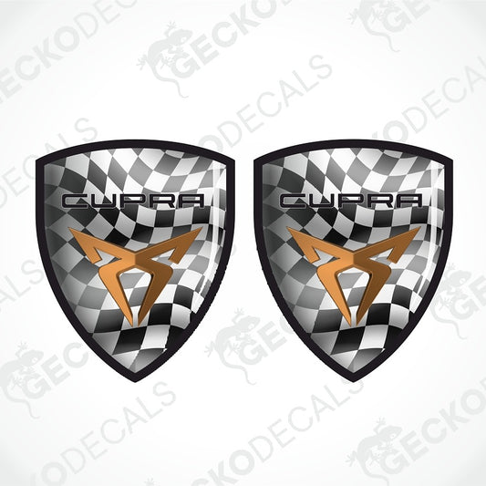 Two matching shield-shaped decals with a black-and-white checkered background, a metallic gold stylized logo, and the word 'CUPRA' across the top, shown on a light gray background with faint watermark text.