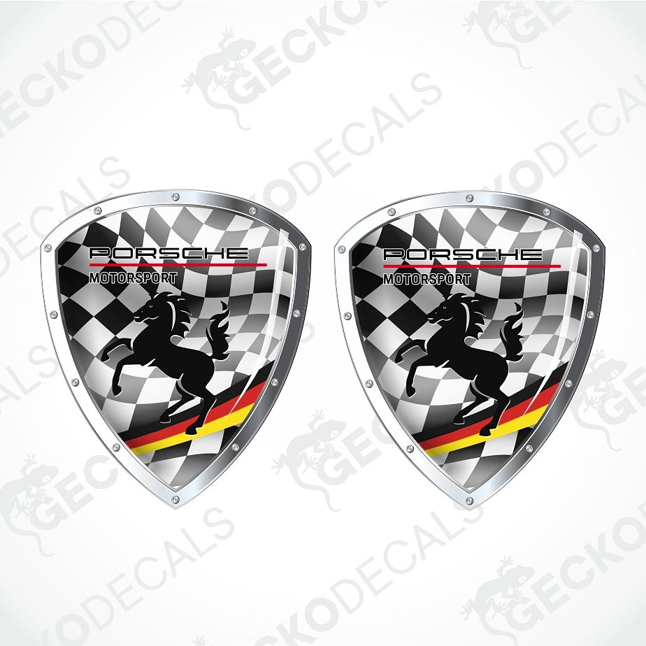 Two Porsche Motorsport shield-shaped decals with a black-and-white checkered background, black horse silhouettes, and red/yellow/green diagonal stripes, shown on a light gray background with repeated watermark text.