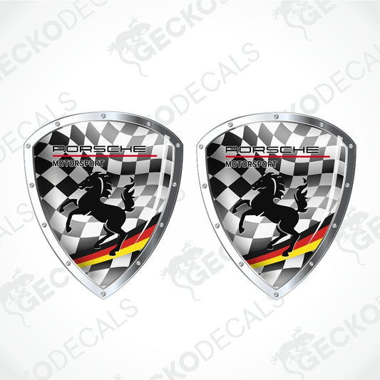Two Porsche Motorsport shield-shaped decals with a black-and-white checkered background, black horse silhouettes, and red/yellow/green diagonal stripes, shown on a light gray background with repeated watermark text.