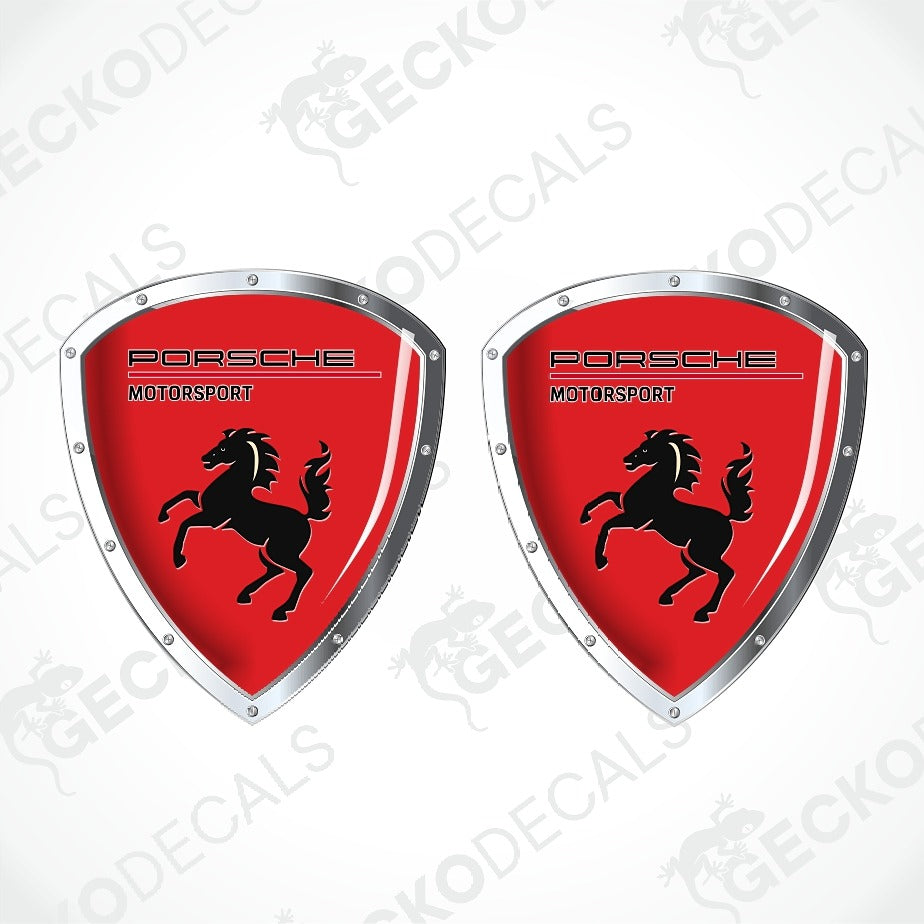 Two Porsche Motorsport shield-shaped decals with a red background, black horse logo, and silver border on a white background with faint watermarks.