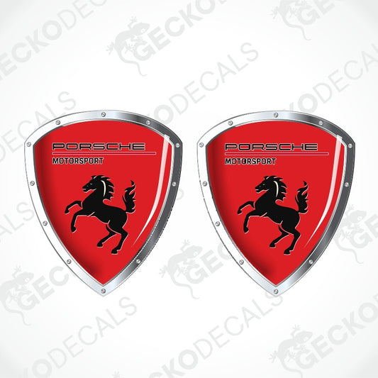 Two Porsche Motorsport shield-shaped decals with a red background, black horse logo, and silver border on a white background with faint watermarks.