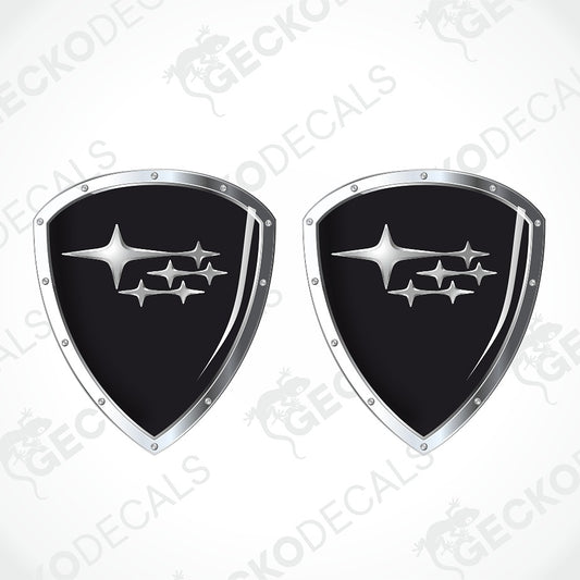 Two identical shield-shaped car decals with a black center and the silver Subaru logo, shown on a light gray background with a faint watermark pattern.