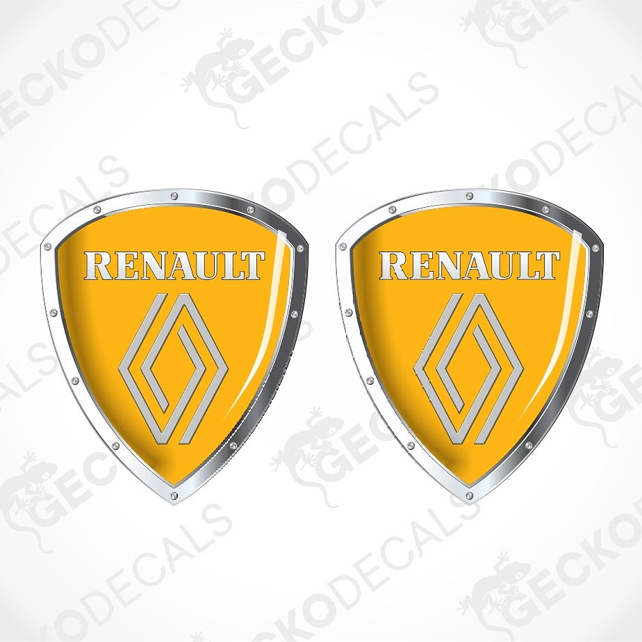 Two Renault shield-shaped decals with a glossy yellow face, silver metallic borders, and the Renault wordmark and logo, shown on a light gray background with faint watermark text.