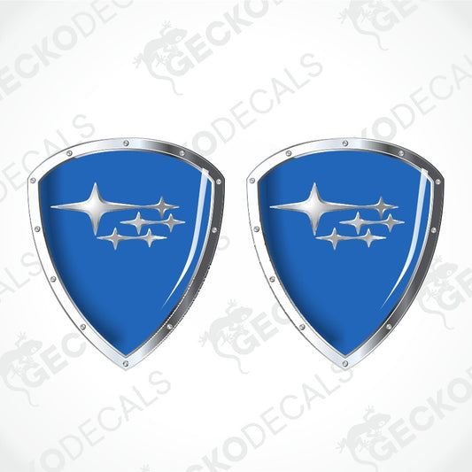 Two identical blue shield-shaped decals with silver borders and a silver Subaru logo, shown on a light gray background with diagonal watermark text.