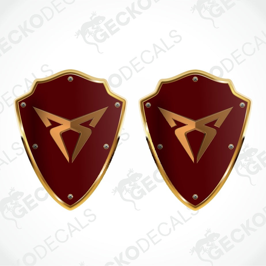 Two identical medieval-style shield-shaped decals with a glossy dark red center, gold border, and a gold emblem, shown on a white background with a faint Geckodecals watermark.