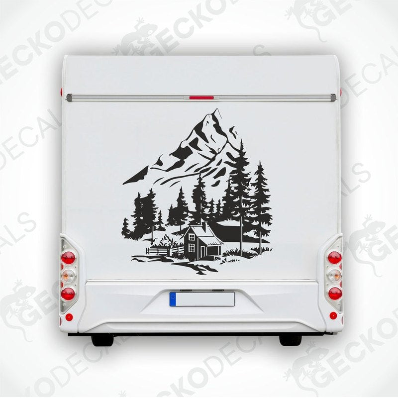 A black decal of a mountain house with trees in the foreground, placed on the rear of a white vehicle.