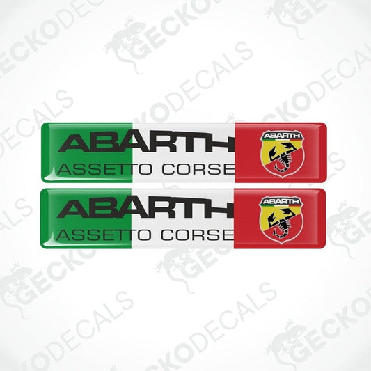 Two vinyl stickers with polyurethane coating. One sticker is red with a yellow shield and the other is green with a black shield, both featuring the 'ABARTH ASSETTO CORSE' text and logos.