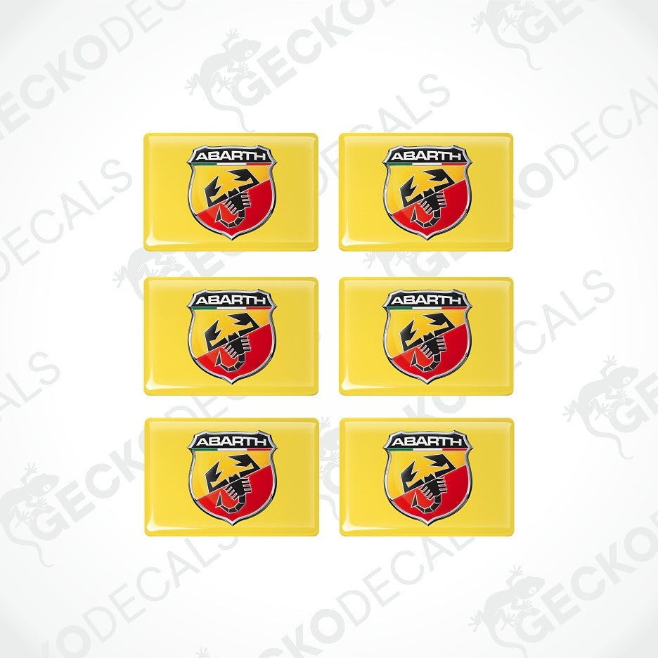 Six yellow rectangular decals arranged in a 2x3 grid on a white background, each featuring the Abarth shield logo with a black scorpion and red and yellow details.