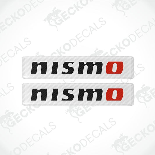 Two rectangular Nismo decal stickers with a carbon-fiber textured background, featuring the word 'nismo' in black with a red 'o' accent.