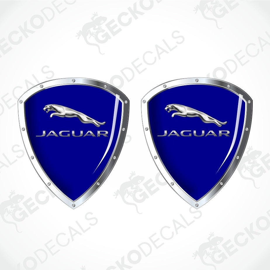 Two identical Jaguar shield-shaped decals on a light gray background with diagonal watermarks. Each decal has a glossy royal blue center, silver border, silver Jaguar leaping cat logo, and silver JAGUAR text.