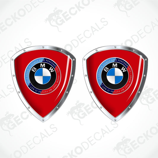 Two red shield-shaped BMW decal designs with silver metallic borders and the BMW roundel logo in the center, shown on a light gray background with faint GECKODECS watermarks.