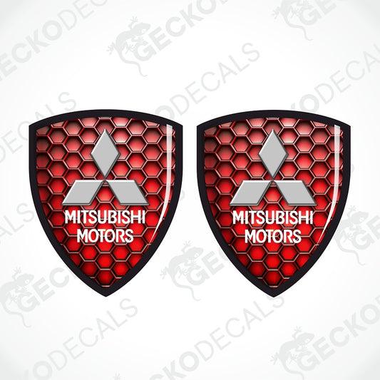 Two identical Mitsubishi Motors shield-shaped decals with a red honeycomb pattern, silver三菱 logo, and white text on a light gray background with diagonal watermarks.