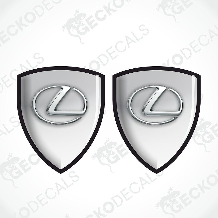 Two identical Lexus shield-shaped decals with a glossy silver and white gradient center, a black border, and the silver Lexus logo in the middle, shown on a light gray background with faint Geckodec watermarks.