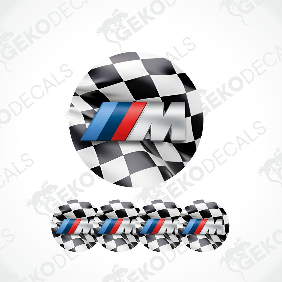 A circular black-and-white checkered sticker or decal featuring a large stylized silver 'M' logo with blue and red stripes, resembling the BMW M branding. Three smaller identical checkered circles appear along the bottom.