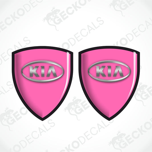 Two pink shield-shaped Kia decal stickers with black borders and silver Kia logos, shown on a white background with faint watermarks.