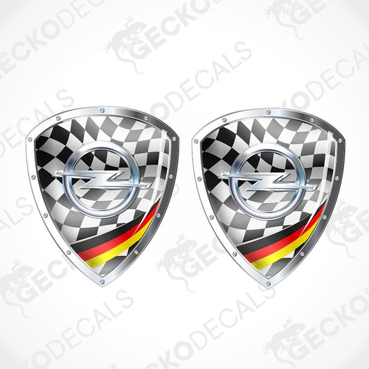 Two identical shield-shaped car decals with a black and white checkered pattern, a silver Opel logo in the center, and a red, black, and yellow German flag stripe at the bottom, shown on a light gray background with a faint watermark.