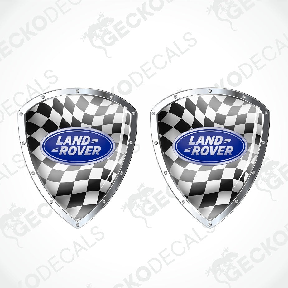 Two Land Rover shield-shaped decals with a black and white checkered flag pattern and a blue oval Land Rover logo in the center, shown on a light gray background with faint watermark text.