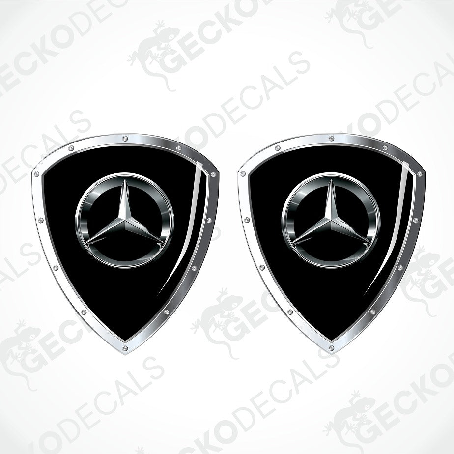 Two Mercedes-Benz shield-shaped decals with a glossy black center and a silver metallic three-pointed star logo, shown on a light gray background with faint watermark text.