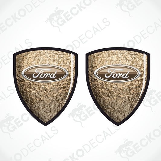 Two Ford shield-shaped decals with a textured metallic gold background, black borders, and a central oval Ford logo, shown on a white background with a faint GECKODECALS watermark.