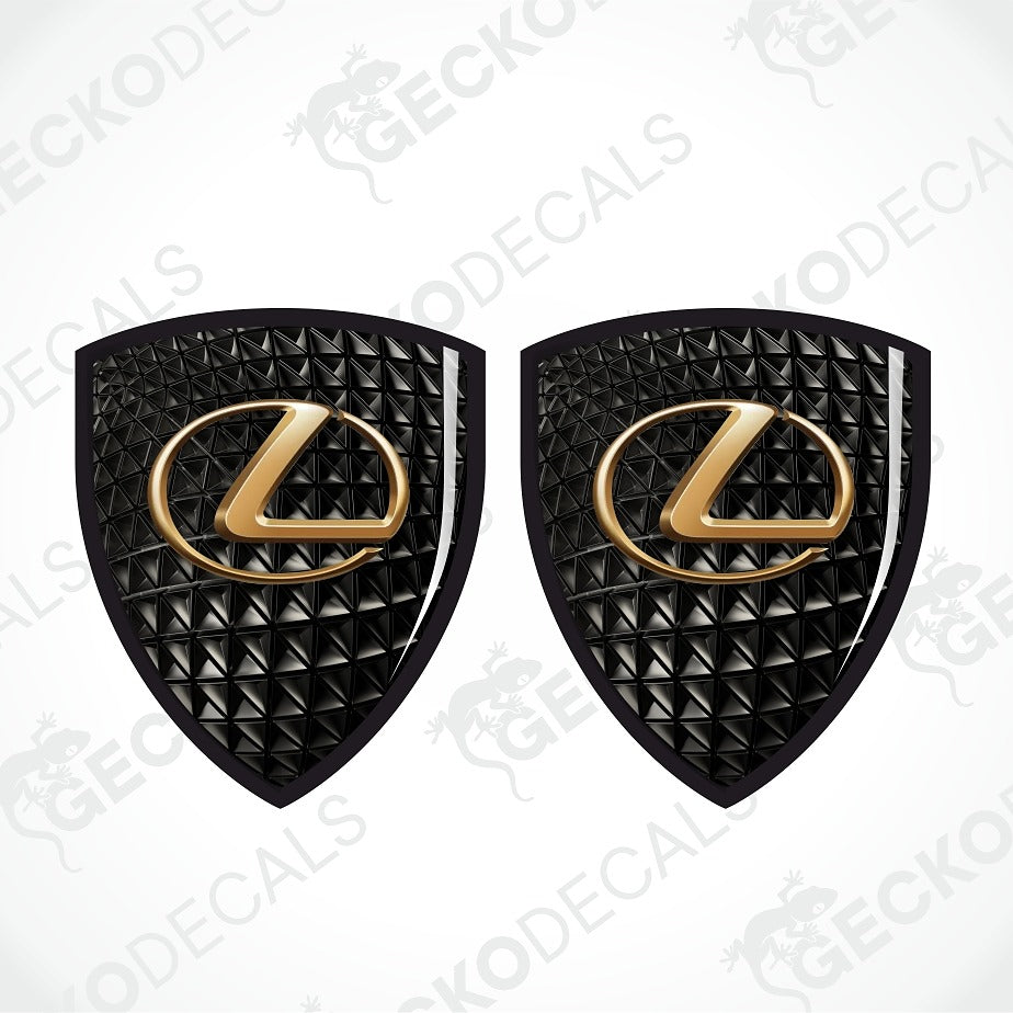 Two black textured Lexus emblem decals with gold Lexus logo centers, displayed side-by-side on a white background with diagonal watermarks.