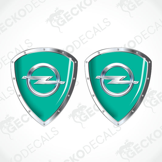 Two identical teal and silver shield-shaped decals with the Opel logo in the center, shown on a light gray background with diagonal watermark text.