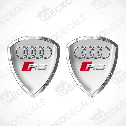 Two silver shield-shaped Audi RS decal stickers with the four-ring logo and red SRS badge, shown on a white background with diagonal watermarks.