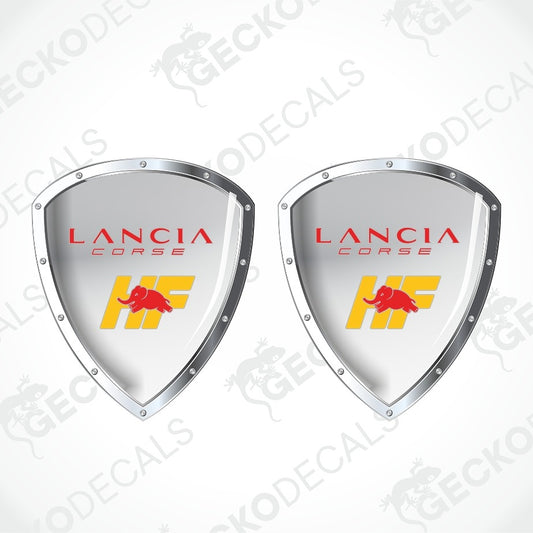 Two identical Lancia Corse decal shield graphics on a white background with faint watermark text. Each shield has a silver border, red 'LANCIA CORSE' text, and a yellow 'HF' logo with a red bull emblem.