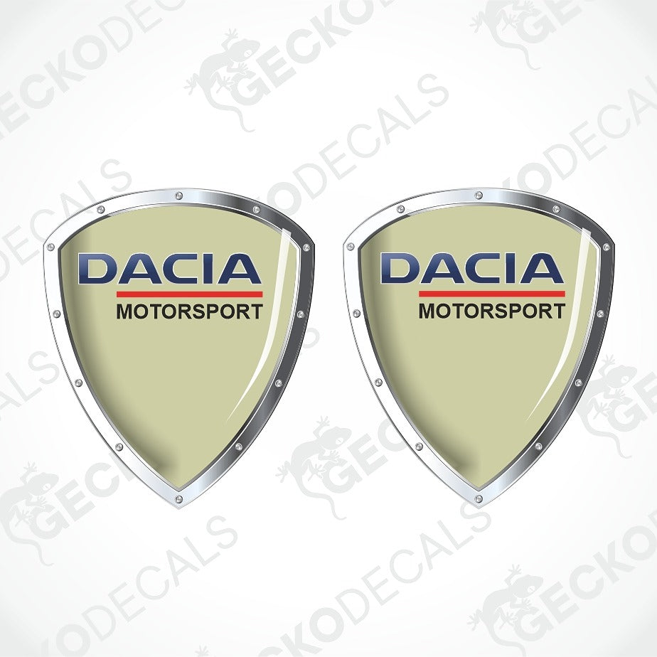 Two identical Dacia Motorsport shield-shaped decals on a white background with diagonal watermarks. The decals feature a light mint green center, silver metallic borders, and the Dacia Motorsport logo in blue and red.
