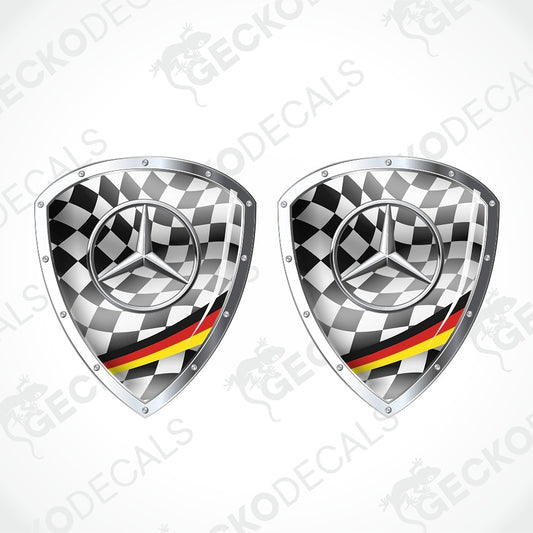 Two Mercedes-Benz shield-shaped decals with a black and white checkered pattern, the silver Mercedes star logo, and a red and yellow stripe resembling the German flag, shown on a light gray background with a faint watermark.