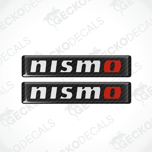 Two rectangular Nismo decals with a black carbon-fiber texture, featuring the word 'nismo' in white and a red 'o' accent, shown on a light gray background with faint watermarks.