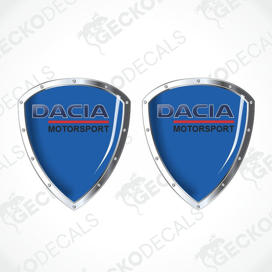 Two identical Dacia Motorsport shield-shaped decals on a white background with diagonal watermarks. The decals feature a light mint green center, silver metallic borders, and the Dacia Motorsport logo in blue and red.